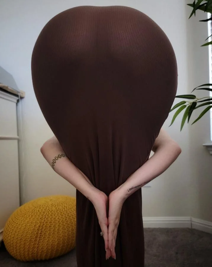 Heart Butt Challenge — Woman in blue dress forming heart shape against dreamy pastel sky backdrop